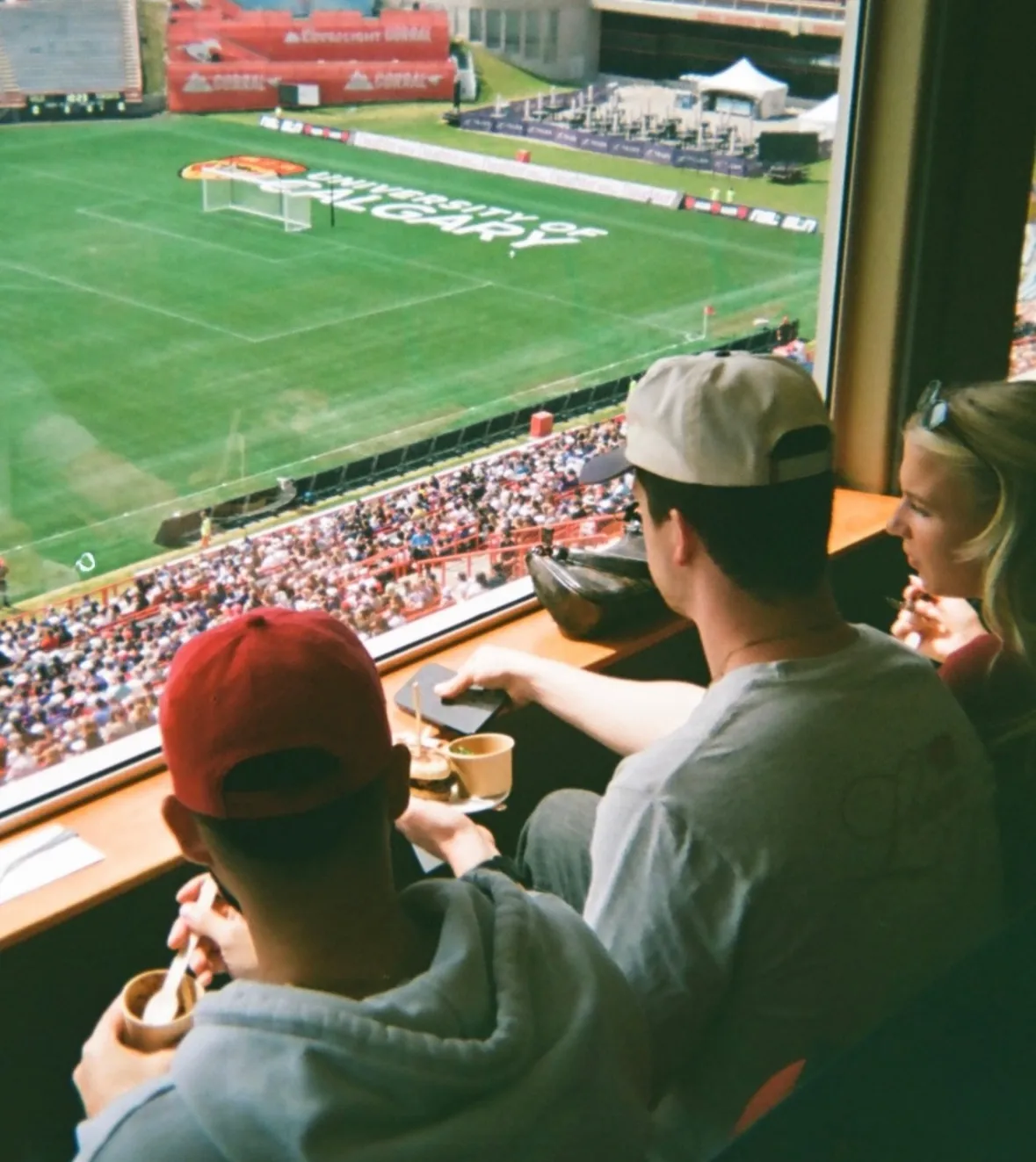 Fans sitting in a suite watching the match on the pitch