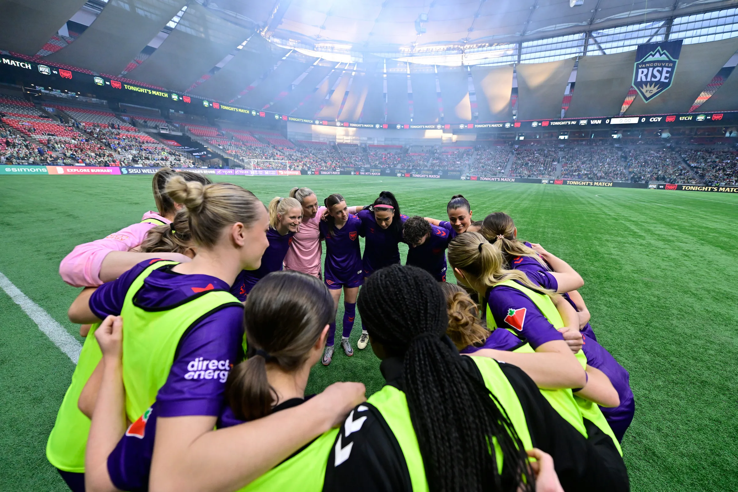 Calgary Wild FC players huddled together on the pitch