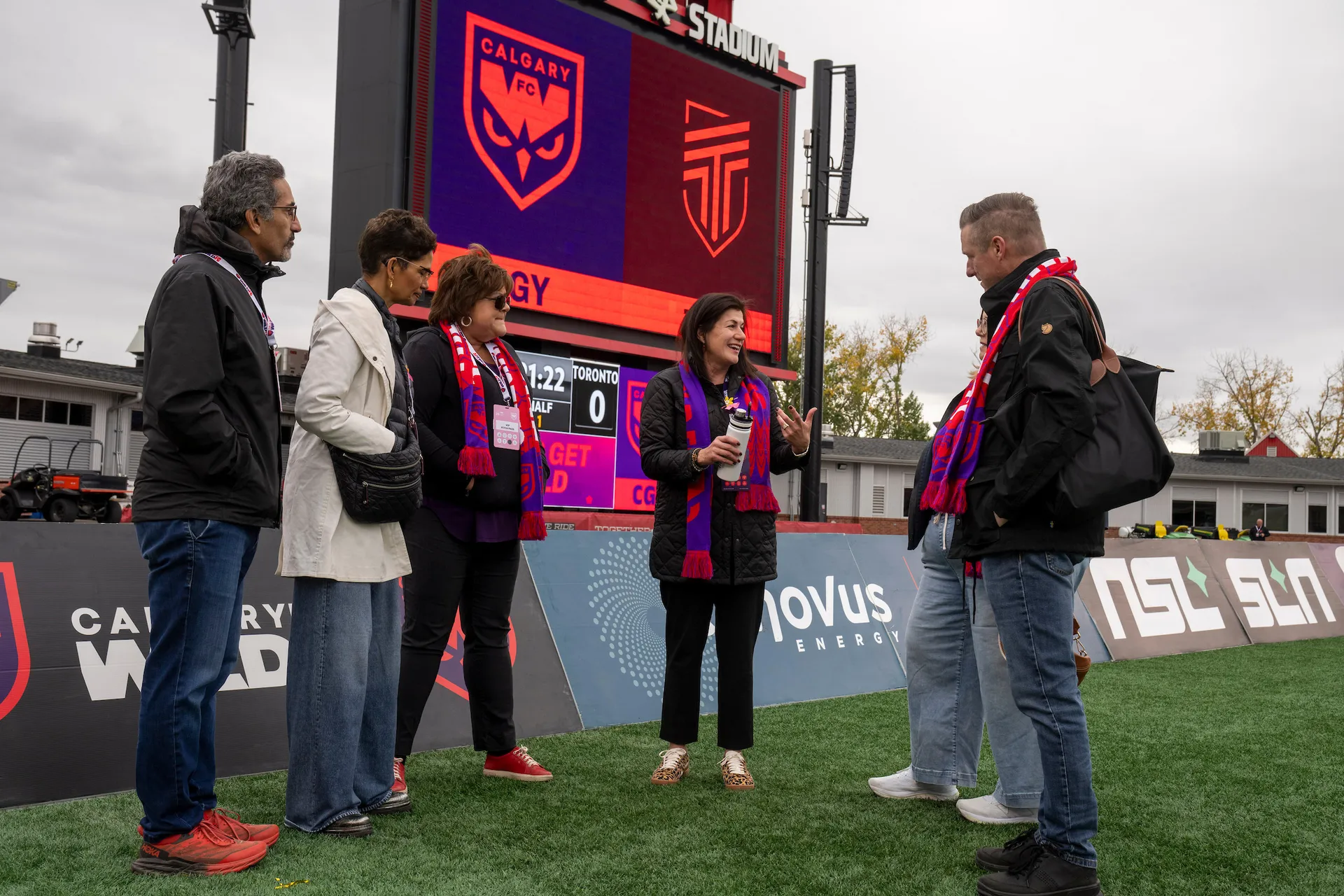Wild FC coach speaking with fans on the pitch in front of a large screen